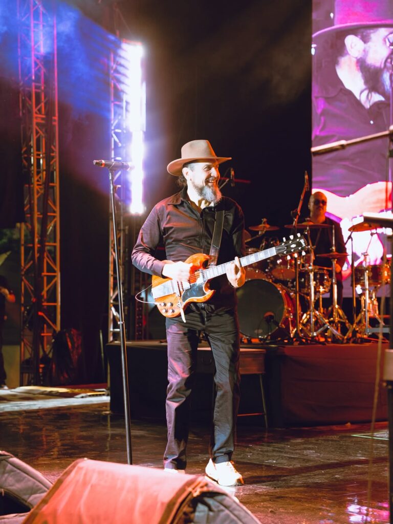 Reyli Barba toca la guitarra durante su presentación en vivo, mostrando su regreso triunfal a los escenarios tras años de ausencia.
