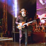 Reyli Barba toca la guitarra durante su presentación en vivo, mostrando su regreso triunfal a los escenarios tras años de ausencia.